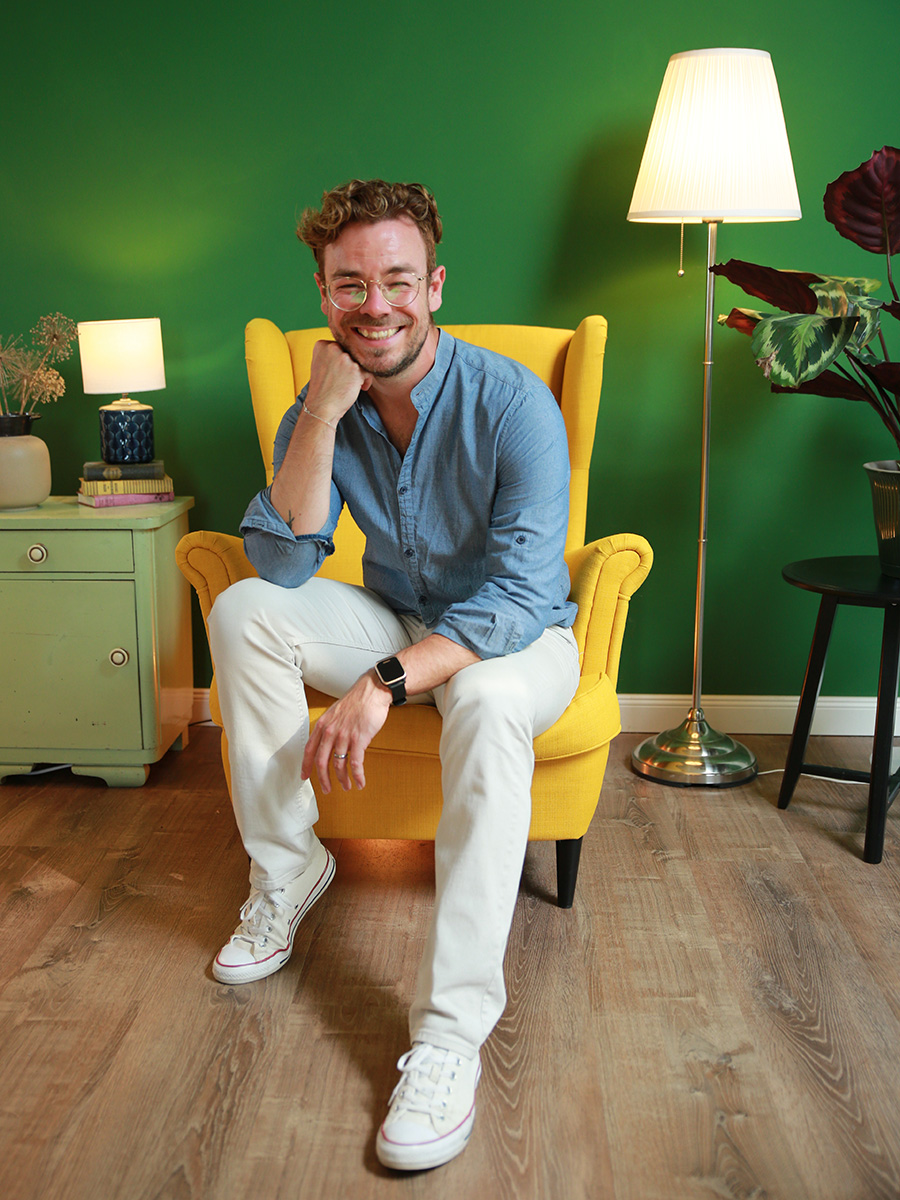 Inhaber Boris Jakob sitzt in gelbem Sessel und lächelt in die Kamera