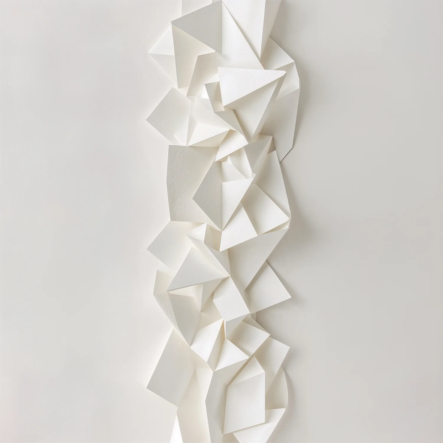Abstrakte, hell beleuchtete Skulptur aus gefalteten Papierstrukturen vor weißem Hintergrund; Sinnbild für haptisches Branding, strategisches Design und die Präzision in der Druckvorstufe bei Impitas.